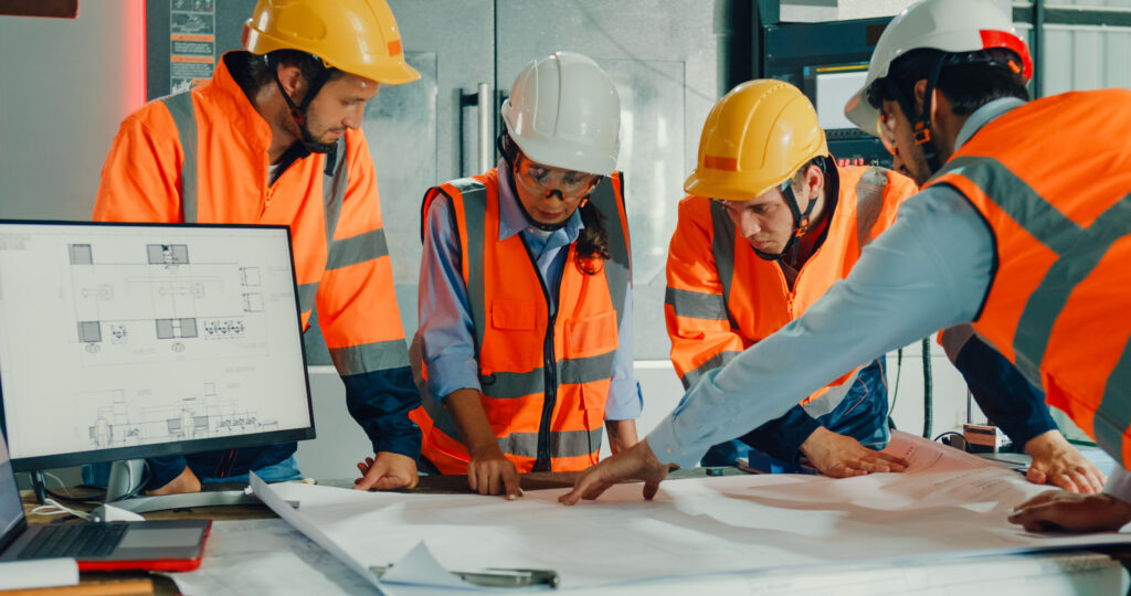 Team of industrial engineers meeting analyze machinery blueprints consult project on table in manufacturing factory. Working in manufacturing plant or production plant.